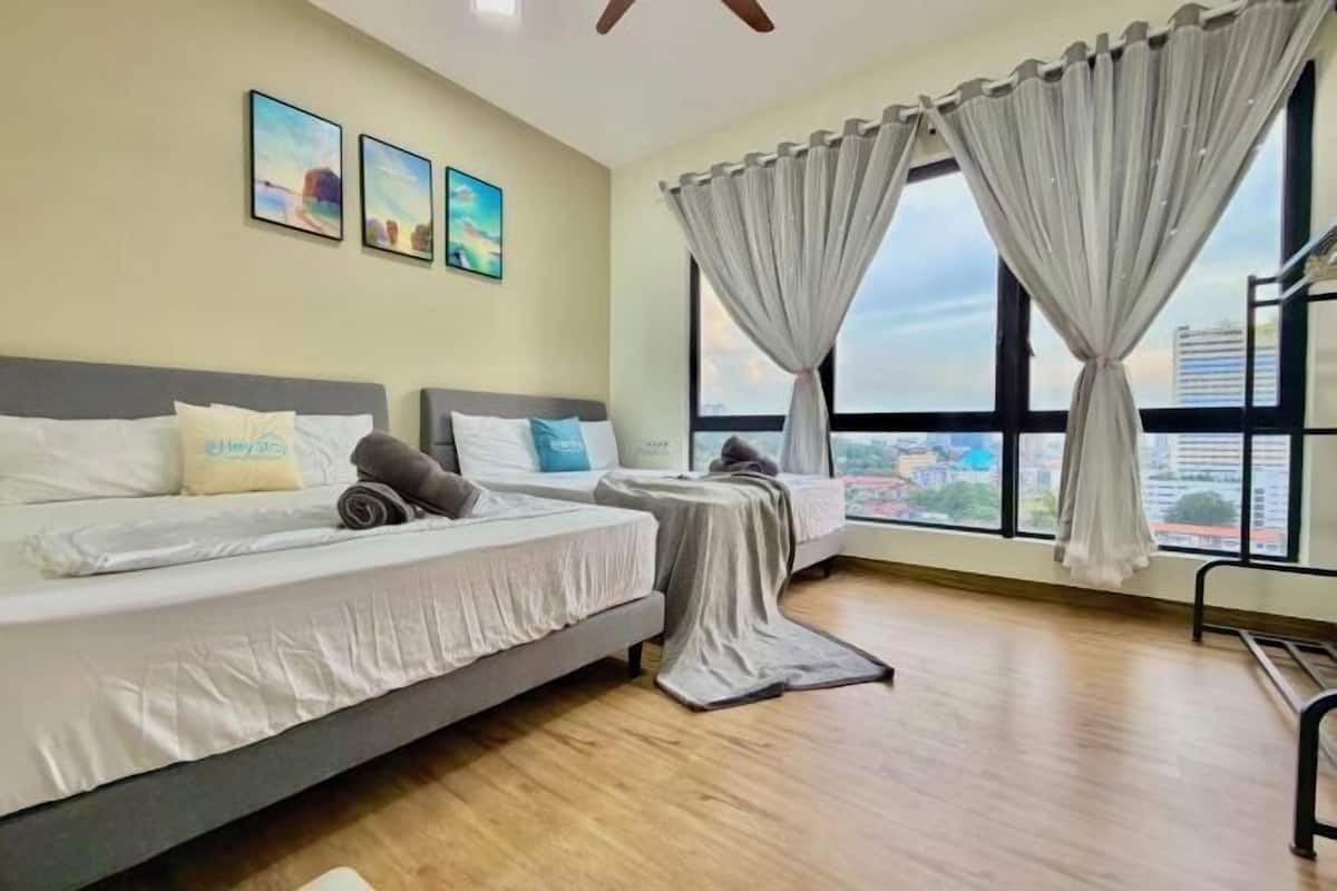 A hotel room with a bed, a window with curtains, and a city view.
