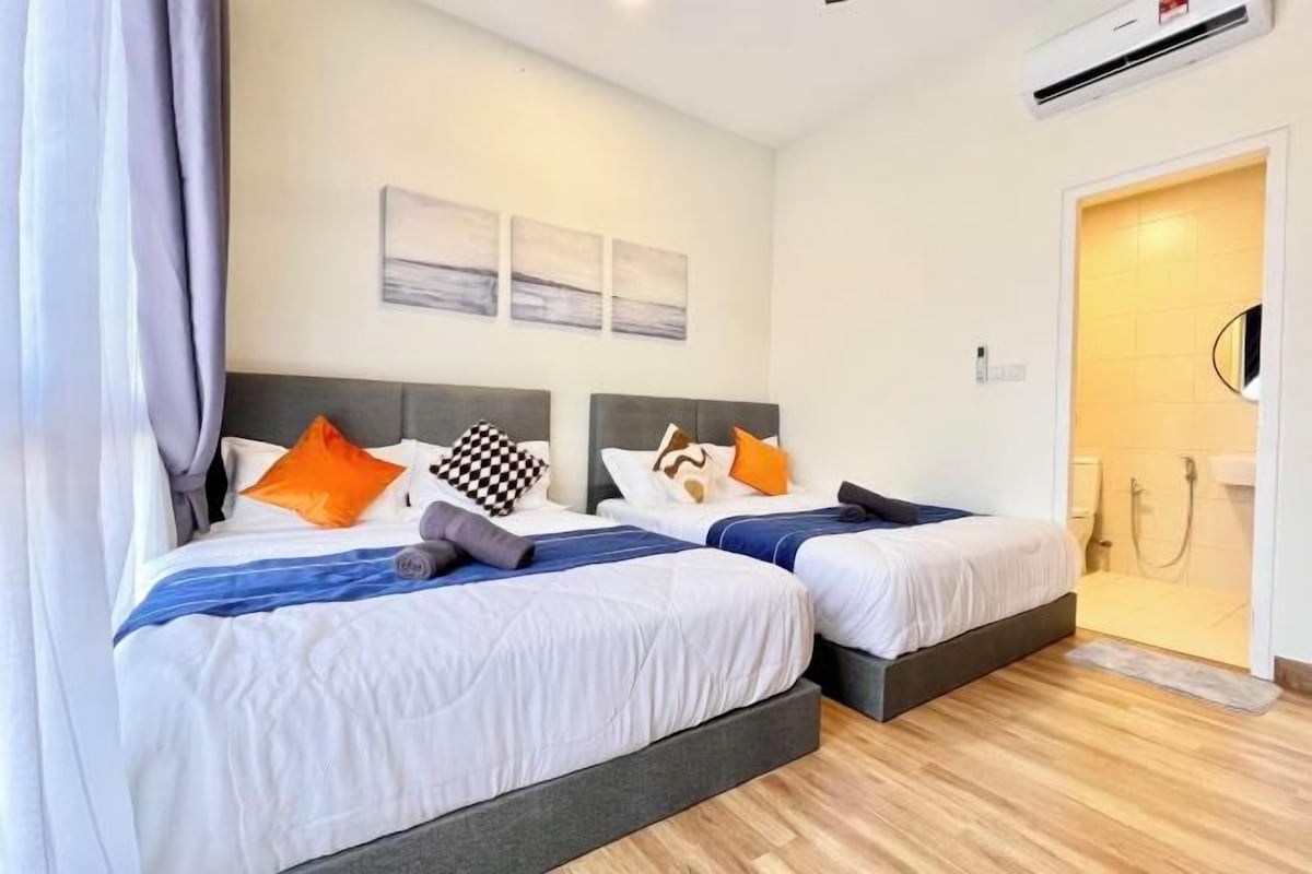 A hotel room with two beds, a grey headboard, white bedding, and a wooden floor.