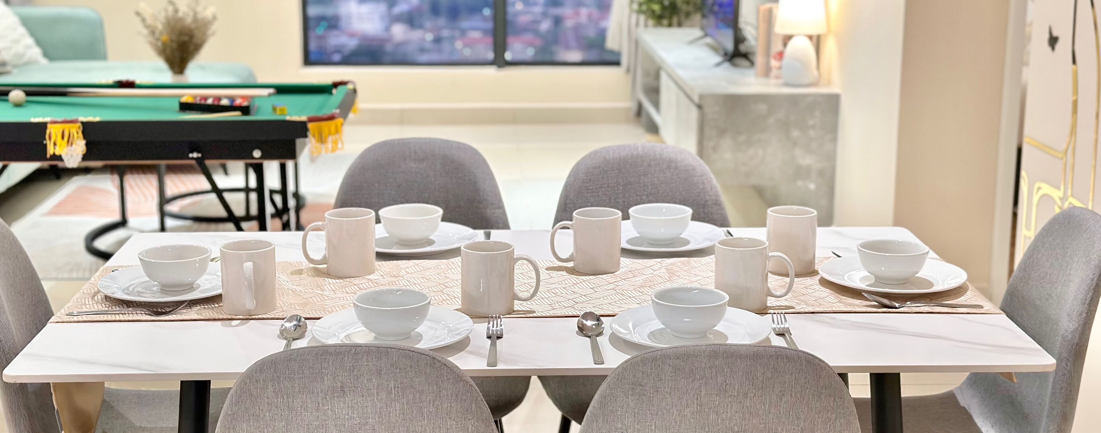 A dining area with a table set for four, including bowls, cups, and cutlery.