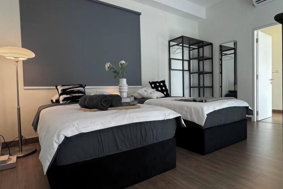 A modern bedroom with two beds, a floor lamp, a mirror, and a wardrobe.
