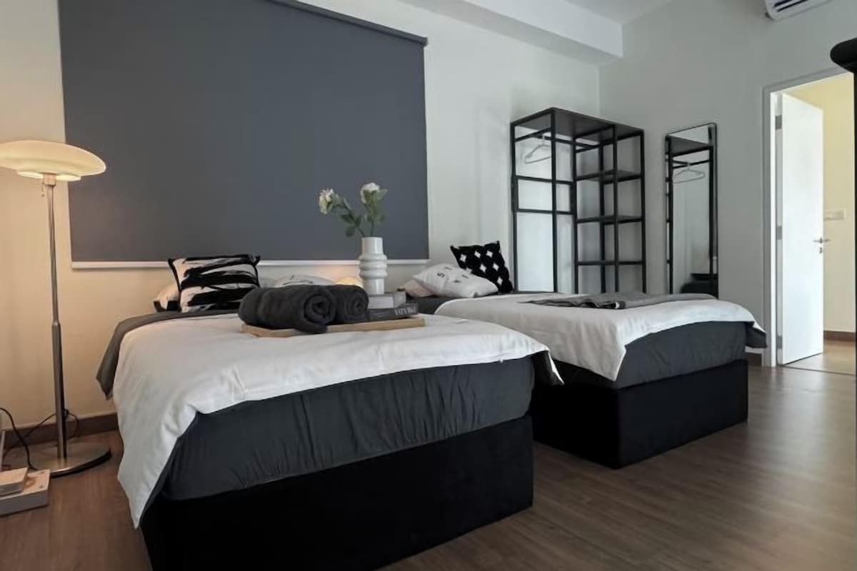 A modern bedroom with two beds, a floor lamp, a mirror, and a wardrobe.