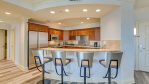 Una cocina moderna con una isla central, taburetes de bar y electrodomésticos integrados.