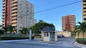 A gated residential area with high-rise apartment buildings, a small security booth, and a parking lot. - Beach Ready Condo than 5 mins. away from your private beach and Margaritaville. (Ocho Rios)
