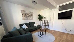 Una sala de estar moderna con un sofá seccional, una mesa de centro, una planta en maceta y un televisor de pantalla plana montado en la pared.
