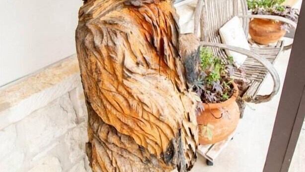 A wooden sculpture of a bear on a stone wall. - Country Inn & Cottages (Fredericksburg)