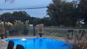 A swimming pool with lounge chairs and potted plants. - Country Inn & Cottages (Fredericksburg)