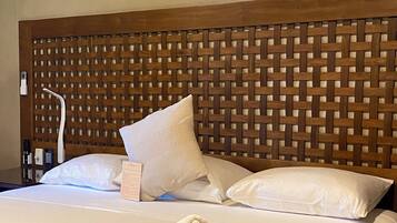 A hotel room with a wooden headboard, white bedding, and a neatly folded towel on the bed.