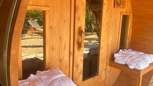 A wooden cabin with a circular door, a bench with towels, and a small table. - El Origen Villas & Spa Puerto Escondido (San Pedro Mixtepec)
