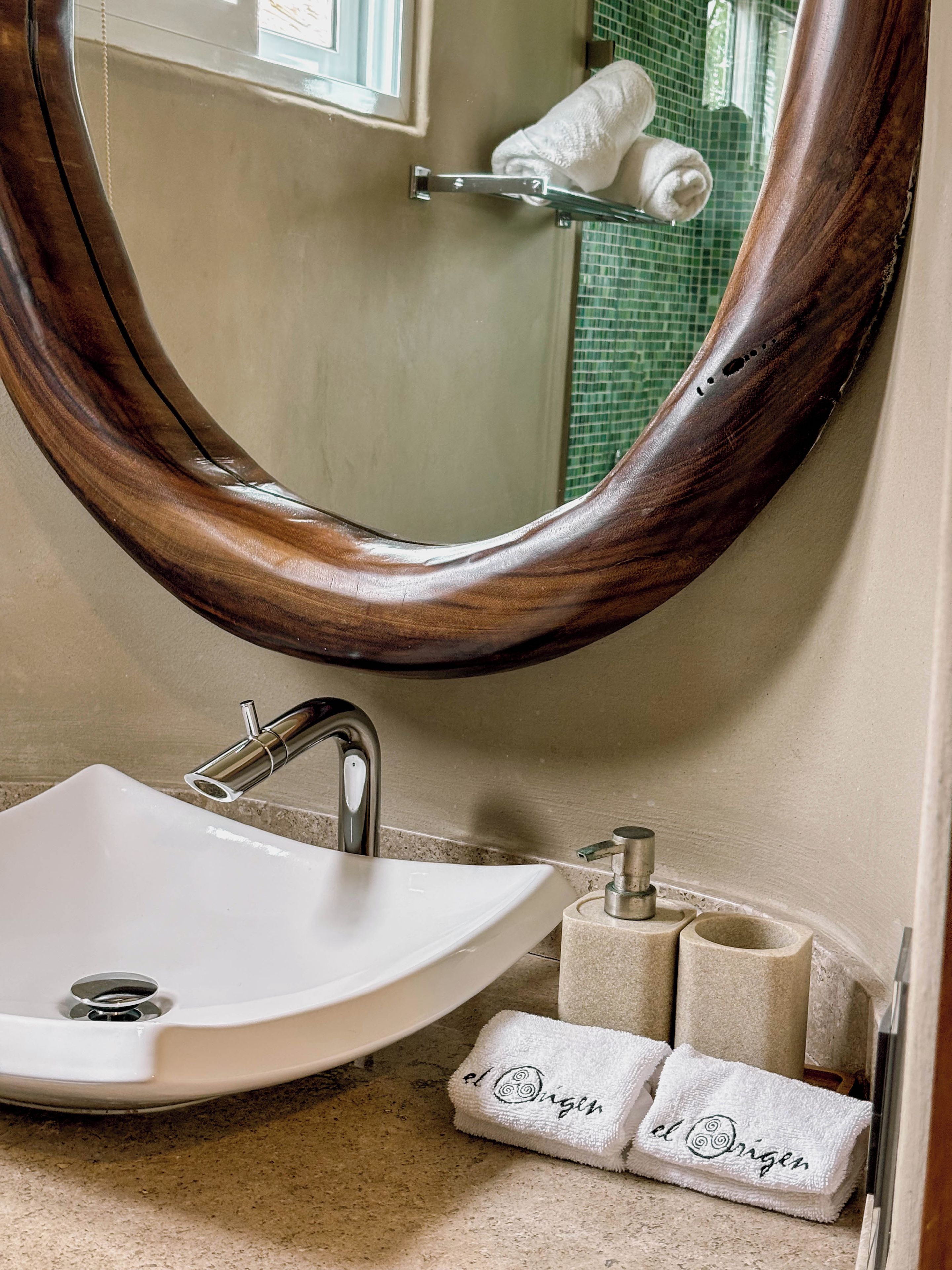 A bathroom with a white sink, a wooden-framed mirror, and a towel rack with two towels.