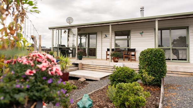 A white building with a covered porch, potted plants, and a small garden area. - Fantail Cottage - 35mins to Raglan &15 mins to shopping centre.
Farm outlook (Whatawhata)