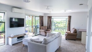 A modern living room with a sofa, chairs, a TV, and a balcony with curtains. - Fantail Cottage - 35mins to Raglan &15 mins to shopping centre.
Farm outlook (Whatawhata)