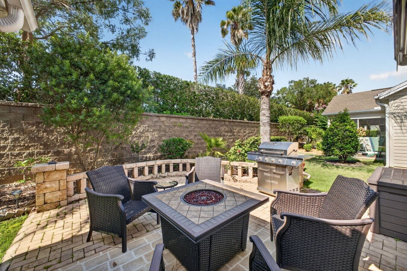 An outdoor patio with wicker furniture, a fire pit, and a grill.