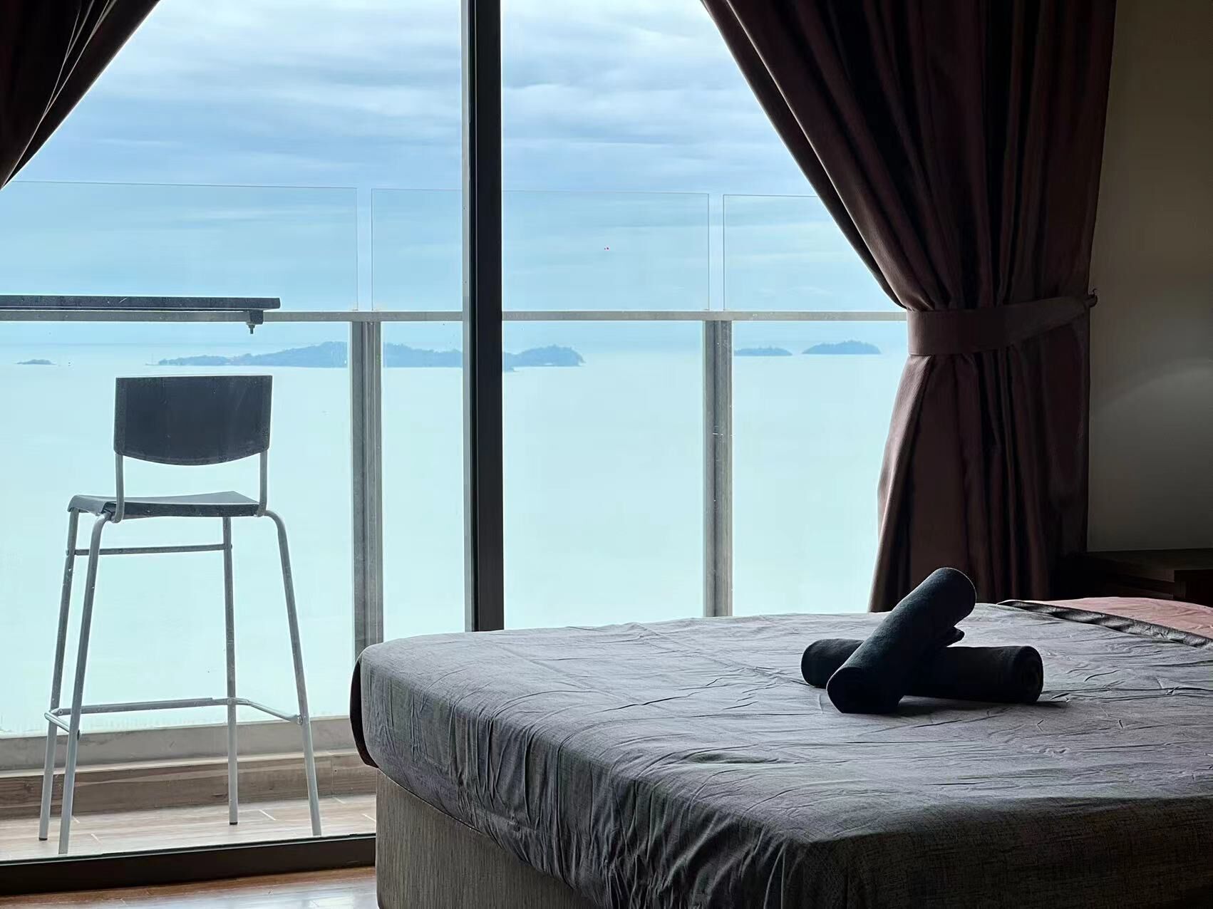 Une chambre à coucher avec un lit, une chaise et une grande fenêtre avec des rideaux.