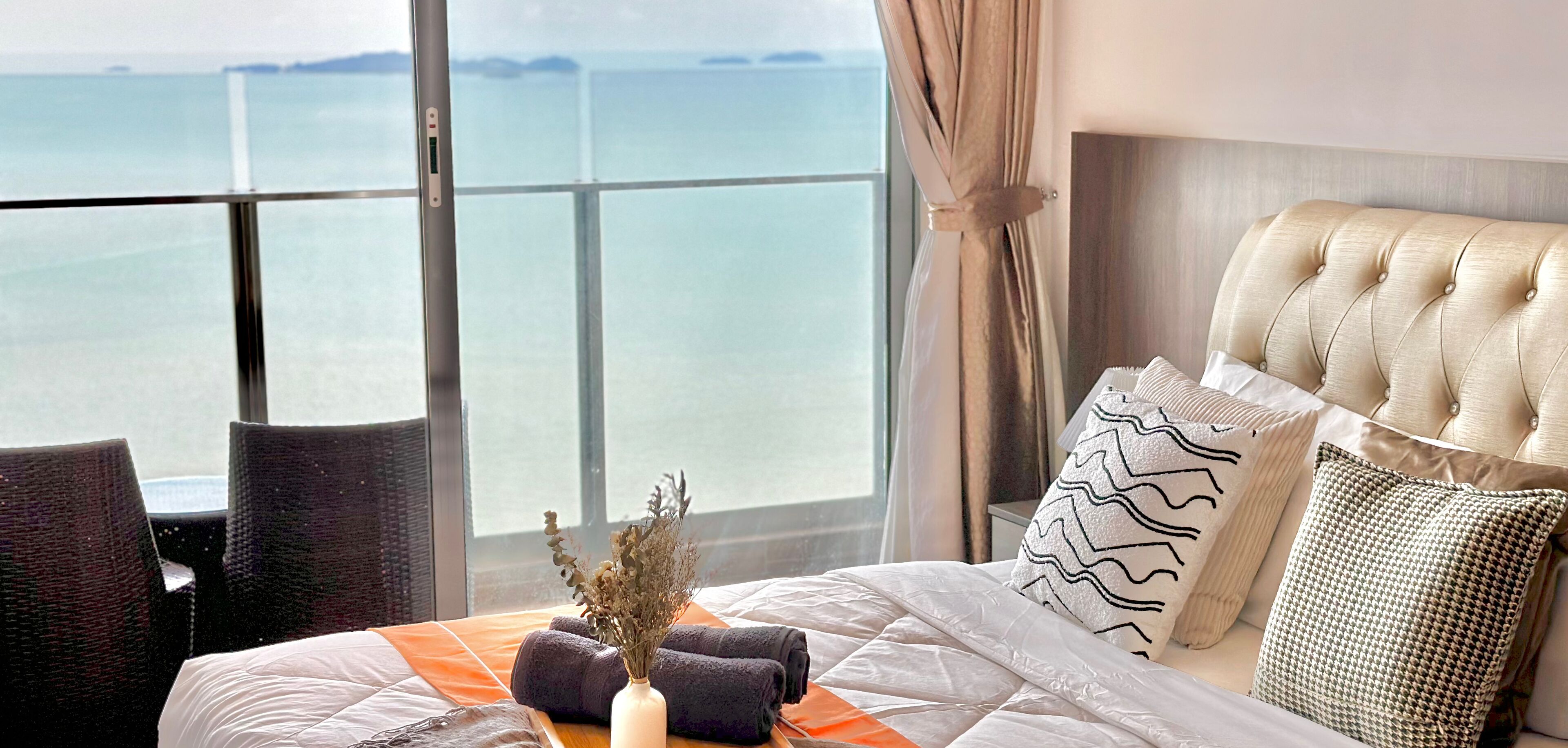 A hotel room with a large window, a bed with a white duvet, and a view of the sea.