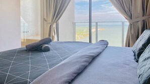 Una camera da letto con un letto grande, vista sul mare e una porta vetrata che dà su un balcone.