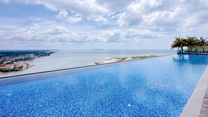Una piscina con vista sul mare e una città in lontananza.