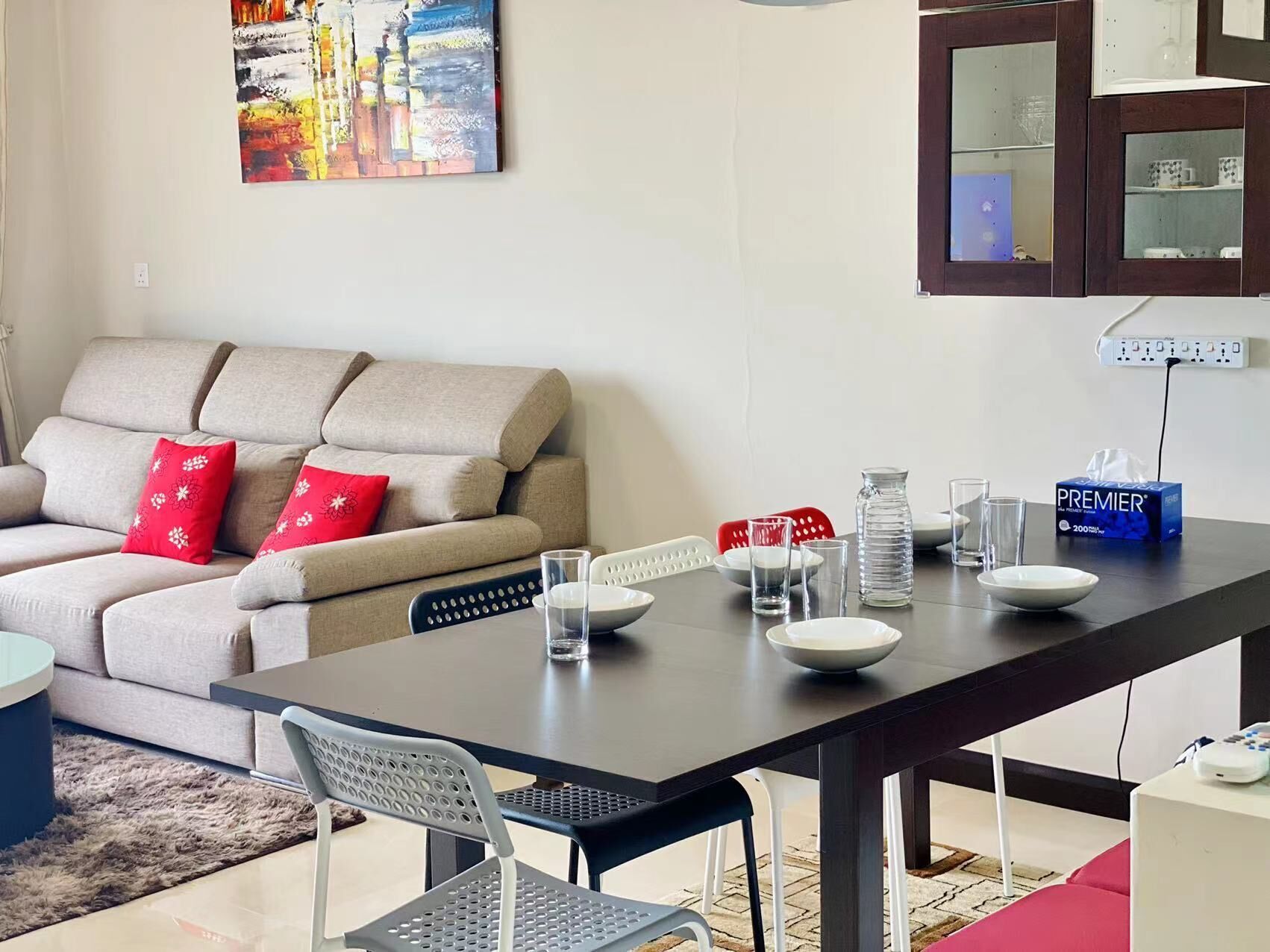 A living room with a sofa, dining table, chairs, and a painting on the wall.