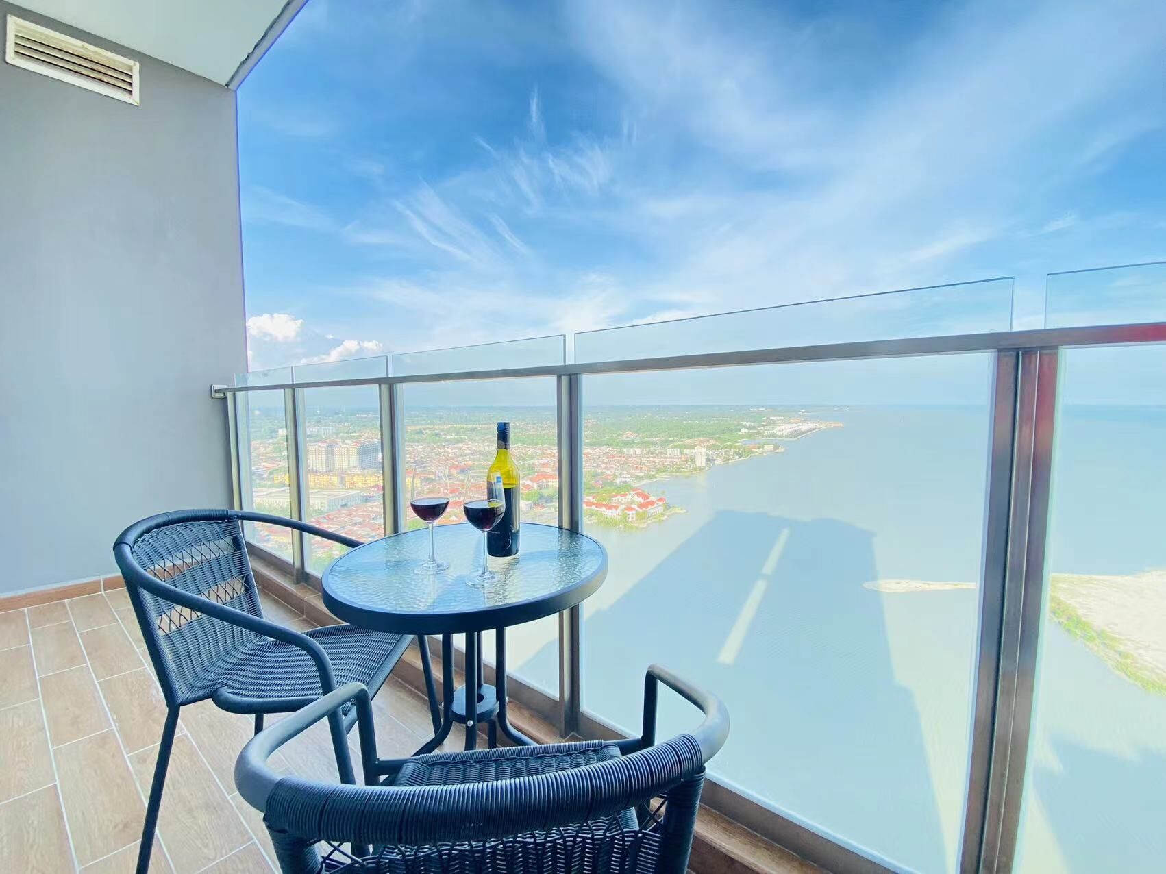 A balcony with a round table, two chairs, and a bottle of wine.