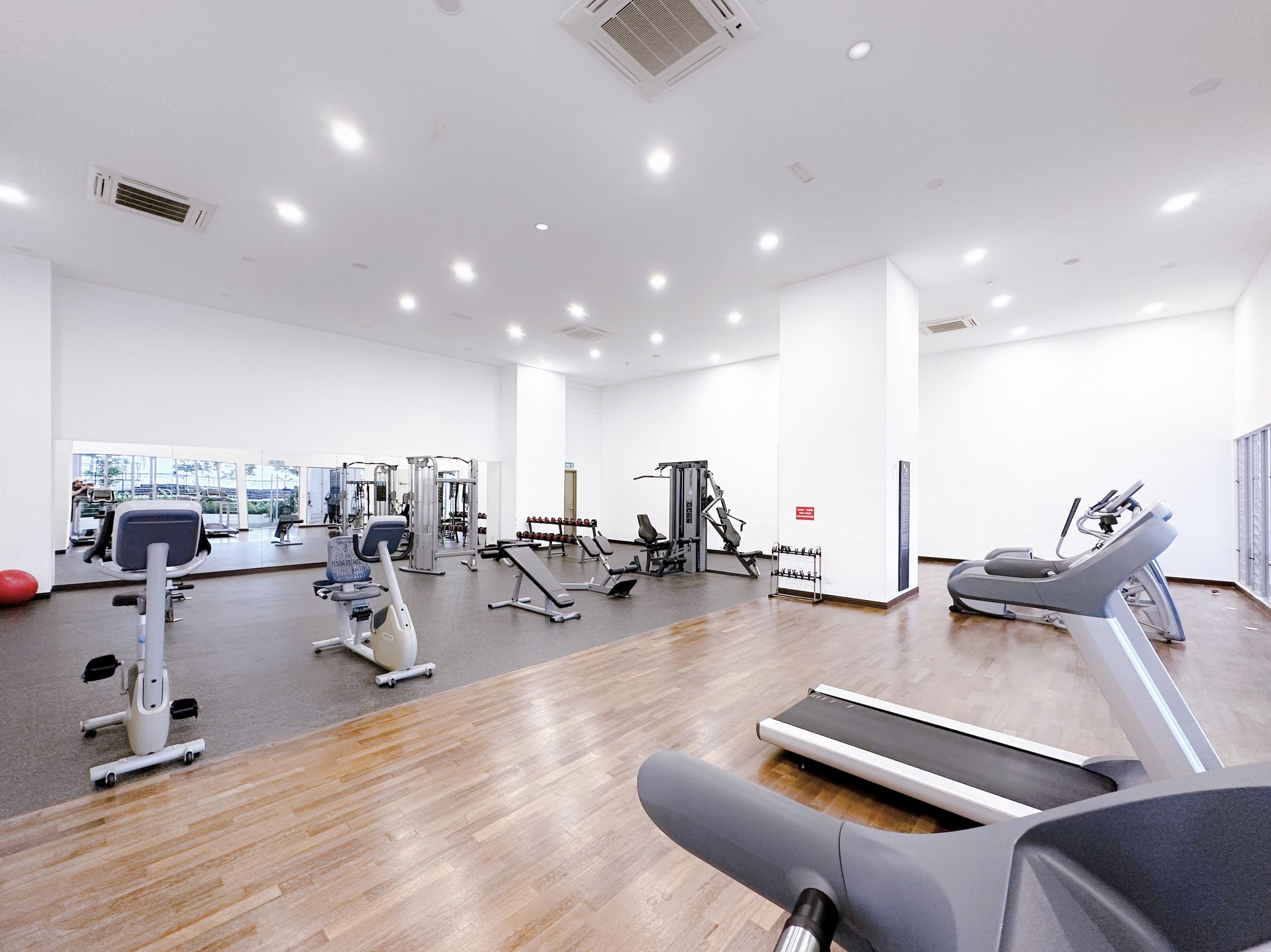 A modern gym with various exercise equipment, a treadmill, and a mirror wall.