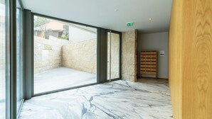 A modern interior with large glass doors leading to an outdoor area, a wooden bookshelf, and a marble floor. - RUAH D - Delightful Studio by LovelyStay (Vila Nova de Gaia)
