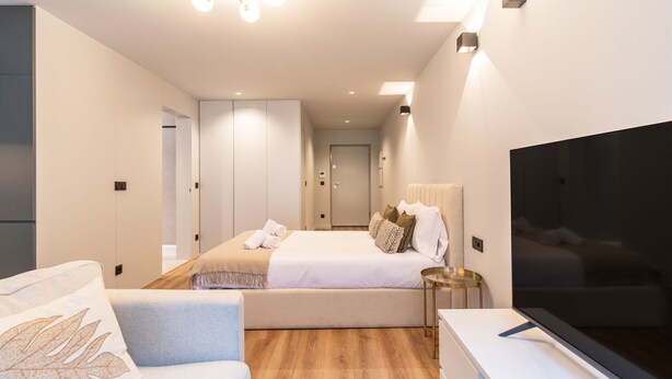 A modern hotel room with a bed, a TV, a sofa, and a bedside table. - RUAH D - Delightful Studio by LovelyStay (Vila Nova de Gaia)