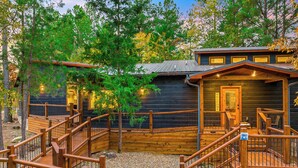 A wooden cabin with a wooden deck and a staircase leading to a covered porch. - 2 Kings + Bunk Haus | Fun Games | Hot Tub | Wheelchair Access, Sleeps 11, Pets (Broken Bow)