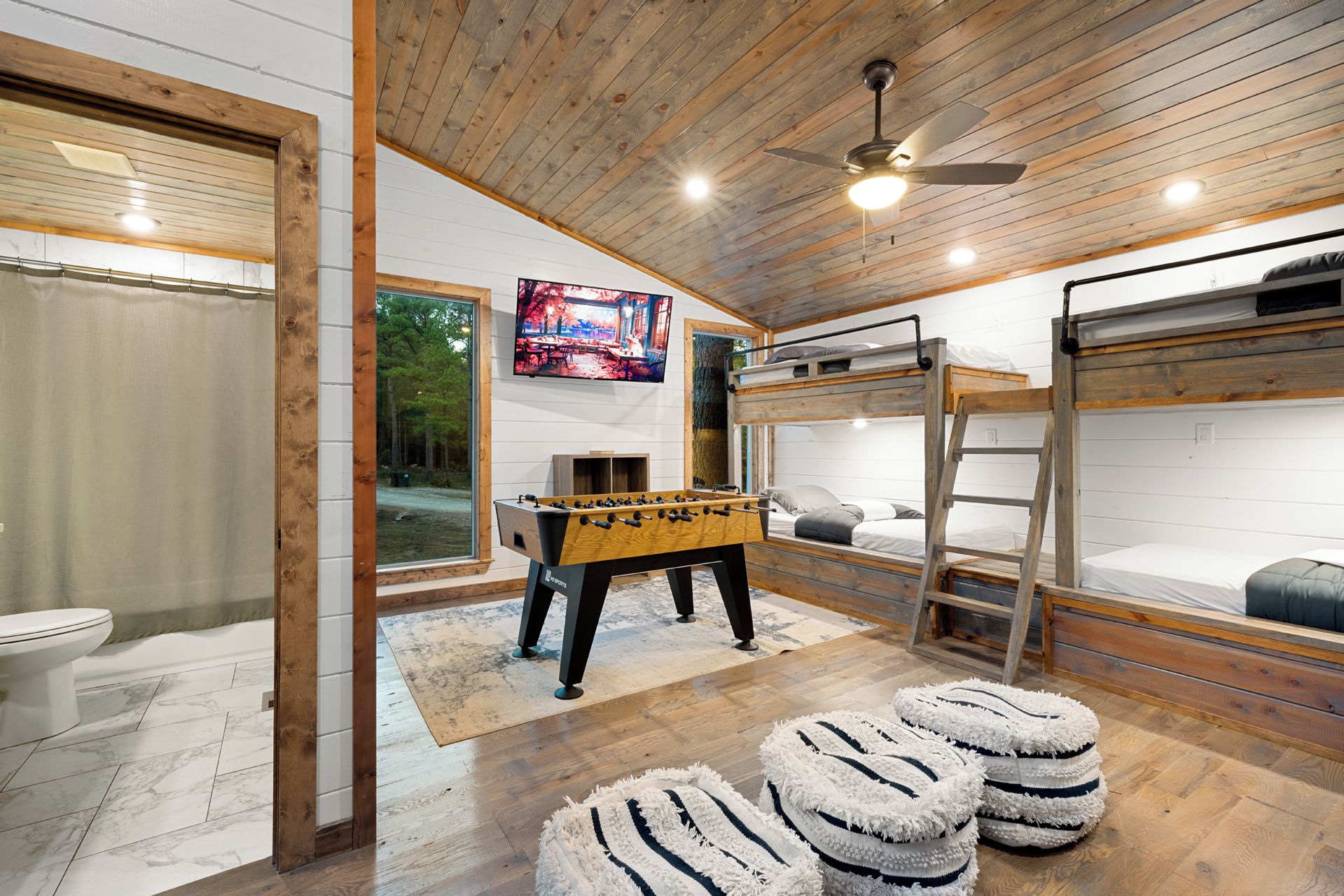 Una habitación acogedora con mesa de futbolín, literas y televisión.