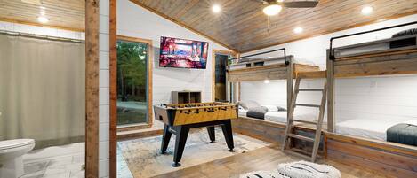 A cozy room with a foosball table, bunk beds, and a television.