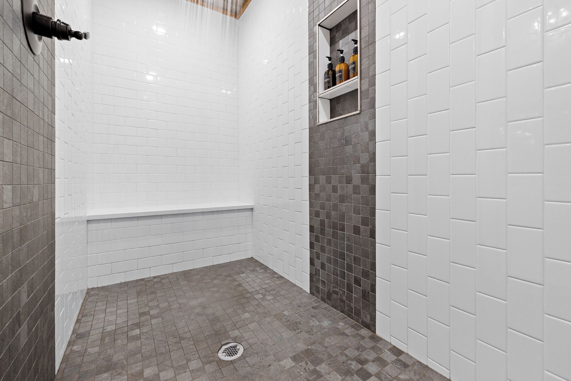 A bathroom with white subway tiles, a gray floor, and a shower area.