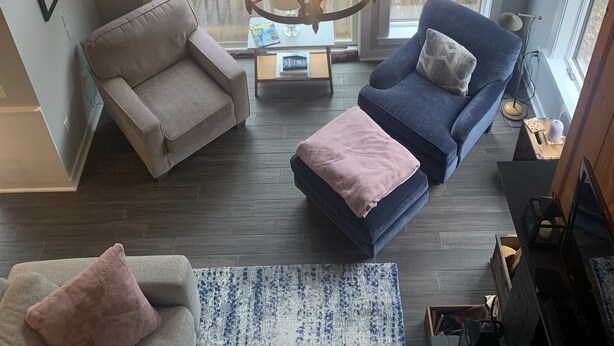A spacious living room with a large chandelier, two sofas, a coffee table, and a view of a wooden deck through large windows. - Newly renovated Townhouse walking distance to Mt.Snow base lodge.  (Dover)