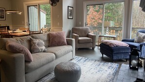 A spacious living room with a large window, a dining area, and a cozy seating arrangement. - Newly renovated Townhouse walking distance to Mt.Snow base lodge.  (Dover)