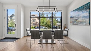 A modern dining area with a large window, a contemporary chandelier, and a view of the outside. - Modern family-sized house close to 17th Ave and downtown (Calgary)