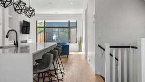 A modern kitchen with a large island, bar stools, and a view to the outside. - Modern family-sized house close to 17th Ave and downtown (Calgary)