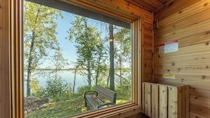 Eine Holzhütte mit einem großen Fenster mit Blick auf einen See und Bäume.