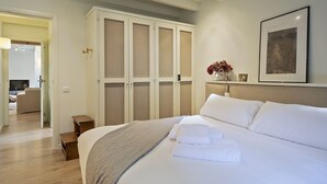 Ein Hotelzimmer mit einem großen Bett, einem Schrank, einem Nachttisch und einem gerahmten Bild an der Wand.