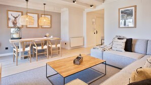 Una sala de estar amplia con una mesa de centro de madera, un sofá y un comedor con una mesa y sillas.