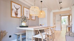 Una cocina moderna con una isla de madera, luces colgantes y cuadros en la pared.