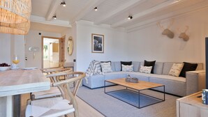 Un salón moderno con un sofá gris, una mesa de centro de madera y sillas de mimbre.