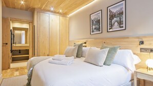 A bedroom with a wooden ceiling, a bed with white linens, a nightstand, and two framed pictures on the wall. - Luderna - Apartamento con jardín Marconi (Arties)