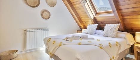 A bedroom with a sloped ceiling, a bed with white linens, a window, and three wall-mounted circular decorations.