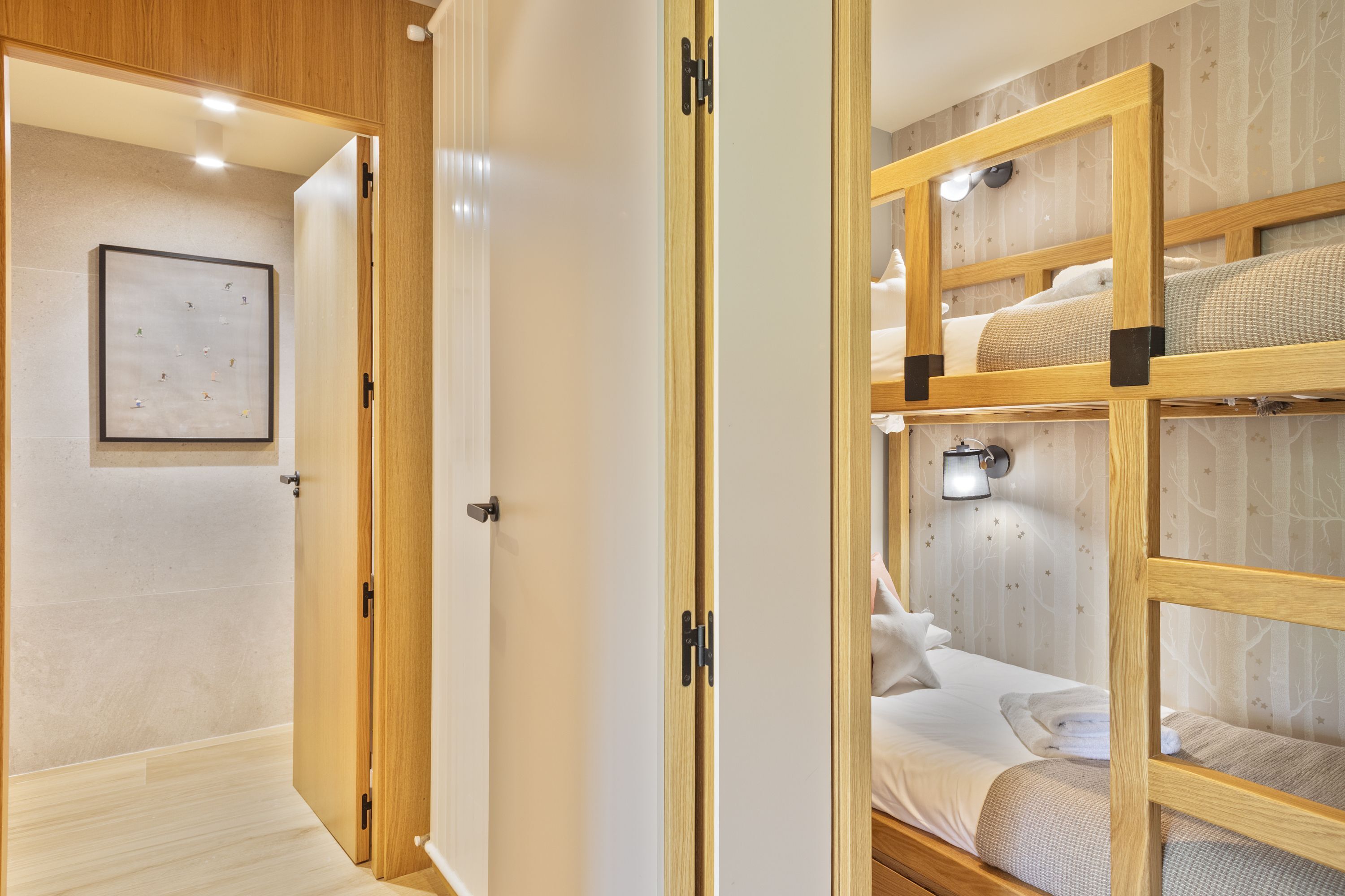 A room with a bunk bed, a framed picture on the wall, and a door leading to another room.