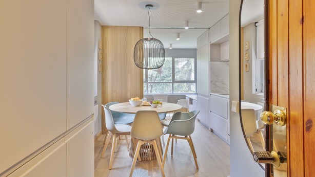 Een moderne eethoek met een ronde tafel, stoelen en een hanglamp.