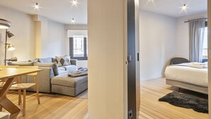 A modern hotel room with a wooden floor, a sofa, a dining table, and a bed. - Luderna - Apartamento con terraza Montanero (Vielha)
