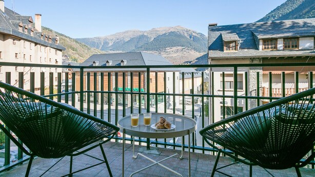 A terrace with two chairs and a table, overlooking a mountain and a town. - Luderna - Apartamento con terraza Montanero (Vielha)