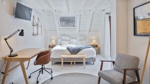 Quarto com cama, escrivaninha, cadeira e mesas de cabeceira.