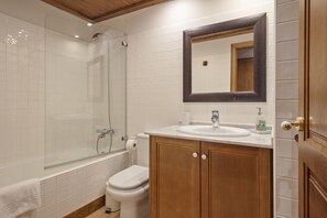 Un bagno con doccia, toilette, lavandino e armadietti in legno.