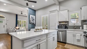 A modern kitchen with white cabinetry, a central island, stainless steel appliances, and a ceiling fan. - Beautiful Retreat Near Historic Downtown McKinney (McKinney)