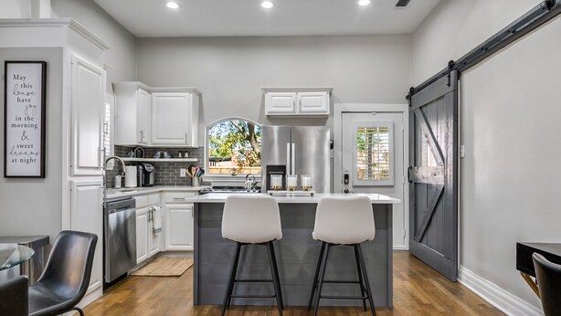 A modern kitchen with white cabinets, stainless steel appliances, and a central island with bar stools. - Beautiful Retreat Near Historic Downtown McKinney (McKinney)