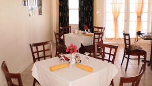 A dining area with a white tablecloth, wooden chairs, and a ceiling fan. - Bahamas Fishing Lodge Hotel
Acklins Island (Salina Point)