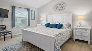 A bedroom with a bed, nightstands, a TV, and a ceiling fan.